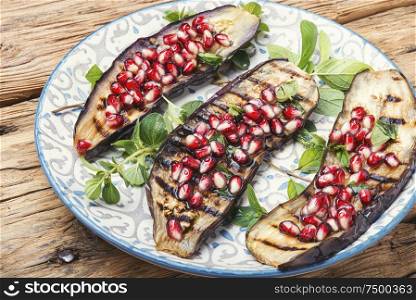 Grilled eggplant cooked with pomegranate.Vegetarian dish.Grilled vegetables in plate. Half an eggplant grill
