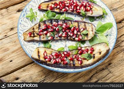 Grilled eggplant cooked with pomegranate.Vegetarian dish.Grilled vegetables in plate. Half an eggplant grill
