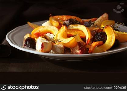 Grilled fall seasonal vegetables on plate over a dark background .. Grilled fall seasonal vegetables on plate over a dark background