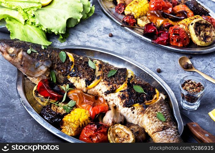 Grilled fish in a tray. Cooked whole grilled fish with vegetable garnish
