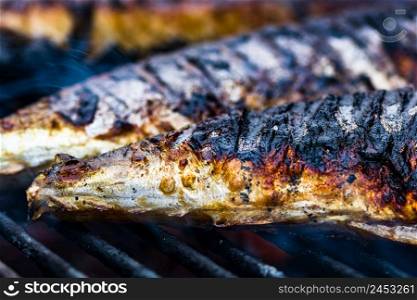 Grilled fish with smoke on a charcoal barbecue. Close up fish on the grill