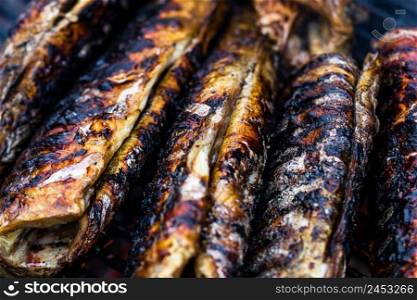 Grilled fish with smoke on a charcoal barbecue. Close up fish on the grill