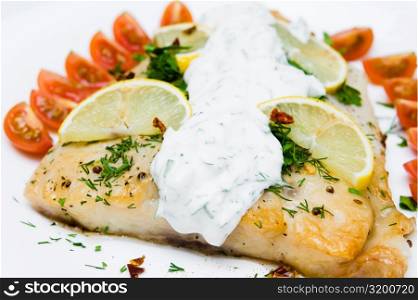 grilled fish with vegetables and cream sauce on white plate