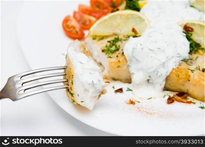 grilled fish with vegetables and cream sauce on white plate