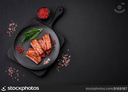 Grilled fresh juicy ribs with salt, spices and herbs on a dark concrete background