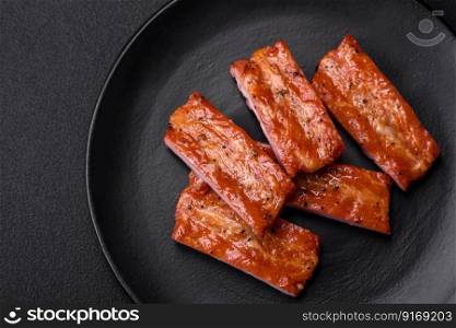 Grilled fresh juicy ribs with salt, spices and herbs on a dark concrete background