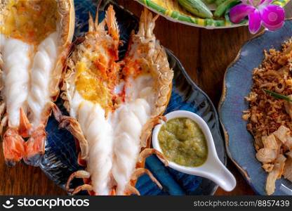 Grilled giant river prawn in a Thai luxury restaurant. Seafood in Thailand. Grilled giant river prawn served on a plate with Thai seafood sauce. Thai cuisine. Grilled giant shrimp on a dinner table.