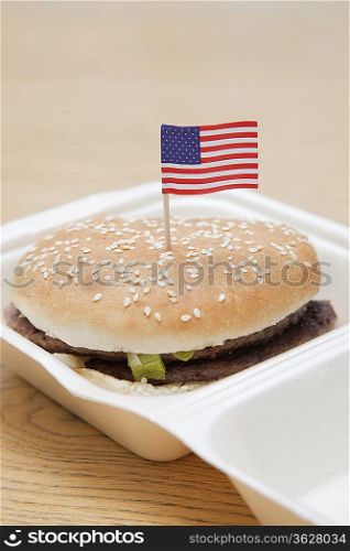 Grilled hamburger with American flag decoration on wooden surface