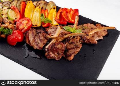 Grilled lamb chops with vegetables on a stone board