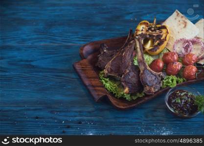 Grilled lamb meat. Grilled lamb meat with vegetable on a blue wooden background