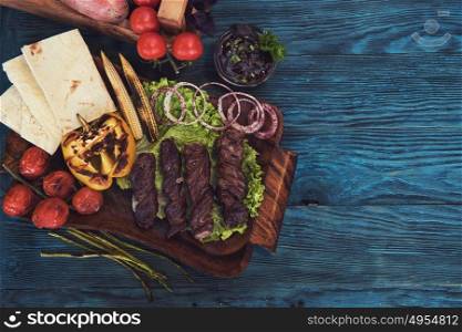 Grilled lamb meat with vegetable on a blue wooden background. Grilled lamb meat