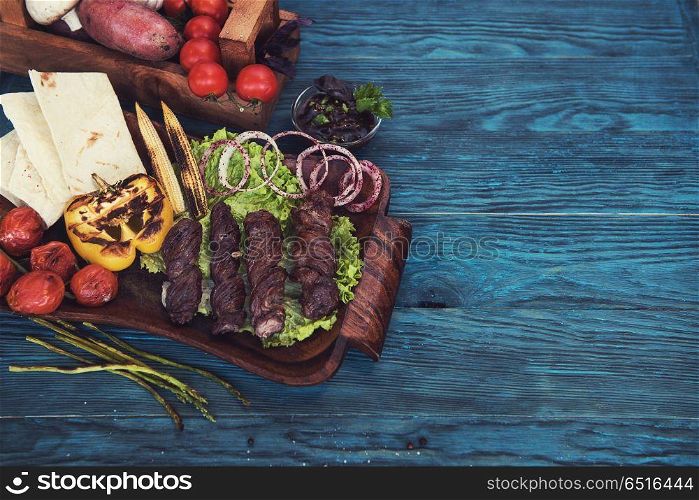 Grilled lamb meat with vegetable on a blue wooden background. Grilled lamb meat. Grilled lamb meat