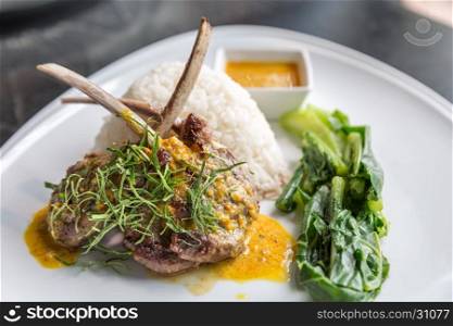 Grilled Lamb steak with spicy yellow sause and green vegetable on jasmine rice.