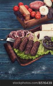 Grilled lula kebab. Grilled lula kebab - meat dish, with vegetable on a blue wooden background