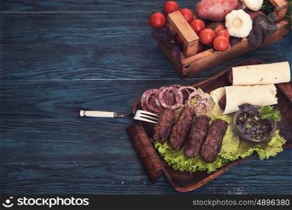Grilled lula kebab - meat dish, with vegetable on a blue wooden background