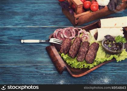Grilled lula kebab - meat dish, with vegetable on a blue wooden background. Grilled lula kebab
