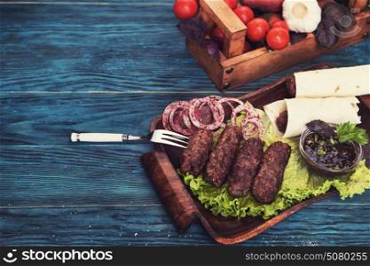 Grilled lula kebab - meat dish, with vegetable on a blue wooden background. Grilled lula kebab