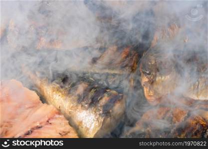 Grilled mackerel fish with smoke on a charcoal barbecue grill.. Grilled mackerel fish with smoke on a charcoal barbecue grill.