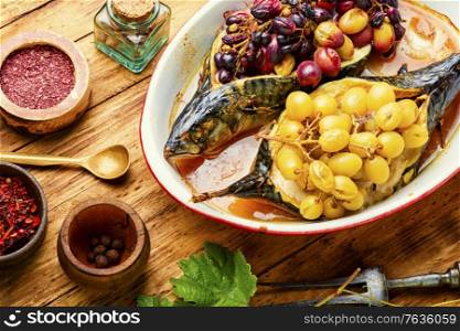 Grilled mackerel or scomber in berry sauce on wooden table. Baked mackerel with grapes