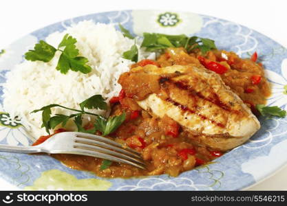 Grilled marinaded chicken served with a spice tomato and red capsicum salsa, in the Caribbean style, and white rice, all garnished with parsley.