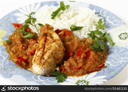 Grilled marinaded chicken served with a spice tomato and red capsicum salsa, in the Caribbean style, and white rice, all garnished with parsley.