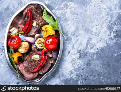 Grilled meat and vegetables. Beef fried meat, grilled vegetables on a plate