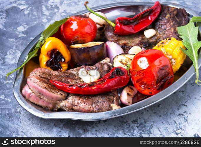 Grilled meat and vegetables. Beef fried meat, grilled vegetables on tray