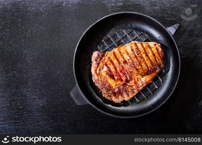 grilled meat in a pan on dark background, top view