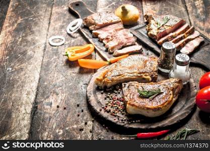 Grilled meat on the old boards with spices. On wooden background.. Grilled meat on the old boards with spices.