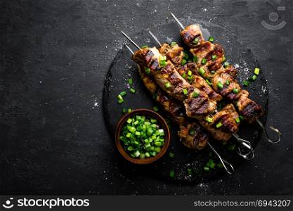 Grilled meat skewers, shish kebab on black background, top view
