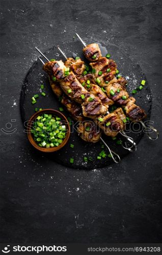 Grilled meat skewers, shish kebab on black background, top view