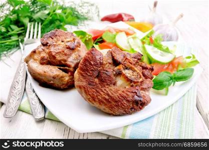 Grilled meat turkey in a white plate with slices of tomato, cucumber, sweet pepper and basil on a wooden boards background