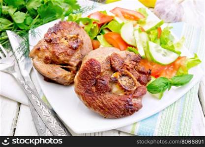 Grilled meat turkey in a white plate with slices of tomato, cucumber and sweet pepper on the background light wooden boards