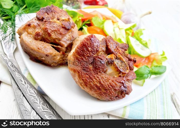 Grilled meat turkey in a white plate with slices of tomato, cucumber and sweet pepper on the background of napkins and wooden boards