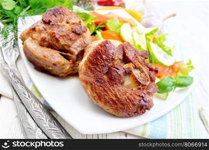 Grilled meat turkey in a white plate with slices of tomato, cucumber and sweet pepper on the background of napkins and wooden boards