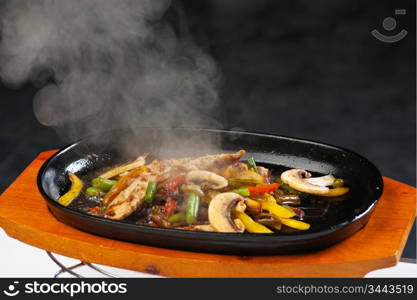 grilled meat with mushrooms and vegetables in a boiling pan