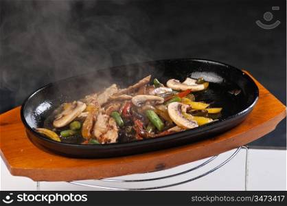 grilled meat with mushrooms and vegetables in a boiling pan