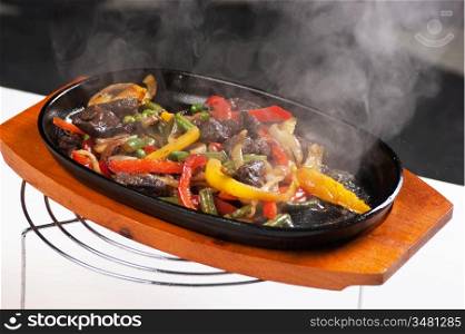 grilled meat with mushrooms and vegetables in a boiling pan