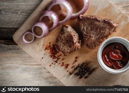 grilled meat with spices and tomato sauce on a worn wooden background