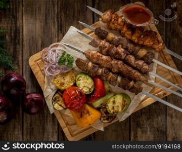 grilled meat with vegetables on skewers on wooden boards, top view. dish on a wooden surface