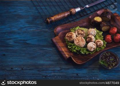 Grilled mushrooms champignons. Grilled mushrooms champignons with vegetable on a blue wooden background