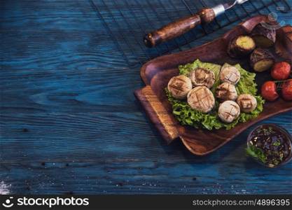Grilled mushrooms champignons with vegetable on a blue wooden background. Grilled mushrooms champignons