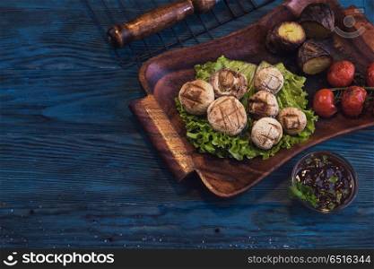 Grilled mushrooms champignons with vegetable on a blue wooden background. Grilled mushrooms champignons. Grilled mushrooms champignons