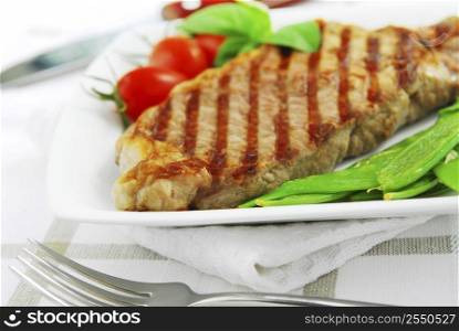 Grilled New York beef steak served on a plate with vegetables