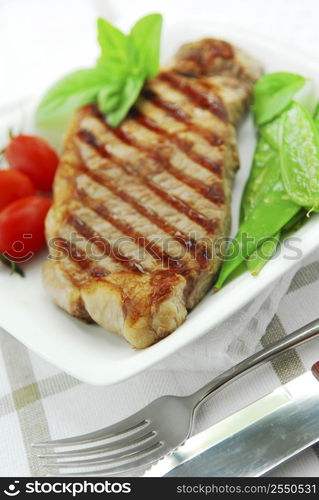 Grilled New York beef steak served on a plate with vegetables