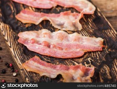 Grilled oily bacon rashers on vintage chopping board close up. Macro