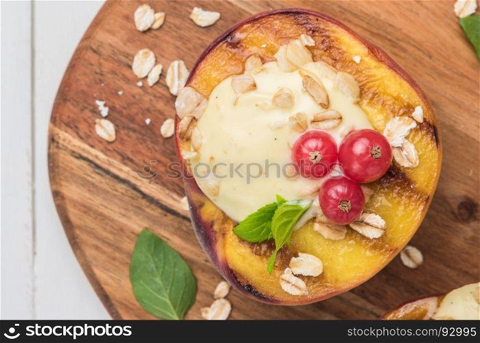 Grilled peaches with yogurt, gooseberries and mint leaves on wooden table