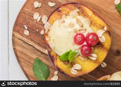 Grilled peaches with yogurt, gooseberries and mint leaves on wooden table