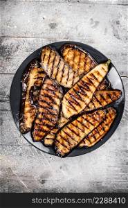 Grilled pieces of eggplant on a plate. On a gray background. High quality photo. Grilled pieces of eggplant on a plate.