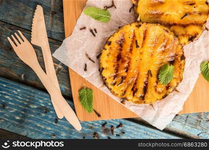 Grilled pineapple slices on wooden table.